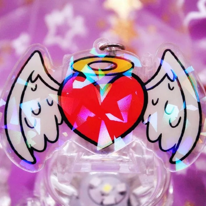 A heart shaped acrylic charm with halo on it.