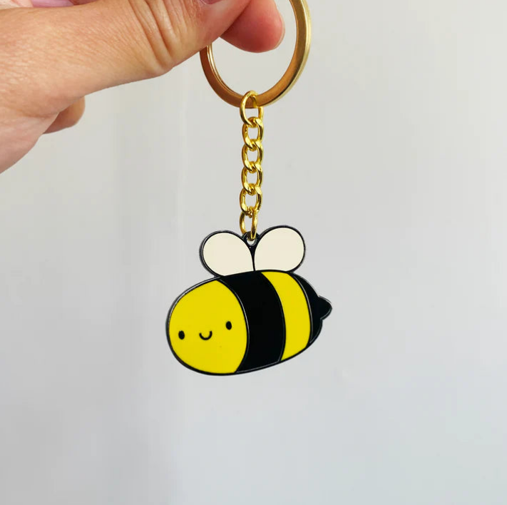 A hand holding bee keychain