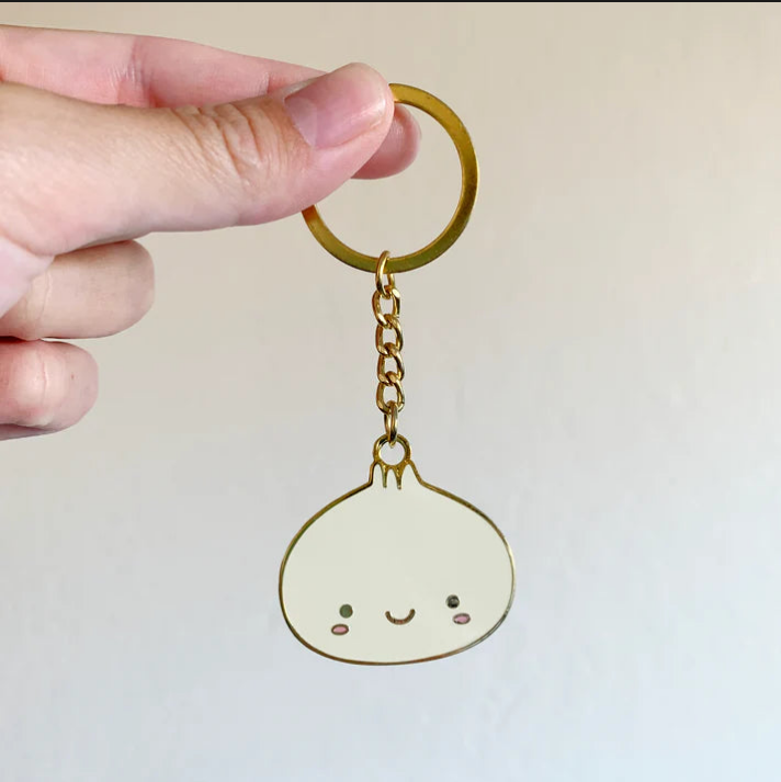 A hand holding a dumpling keychain