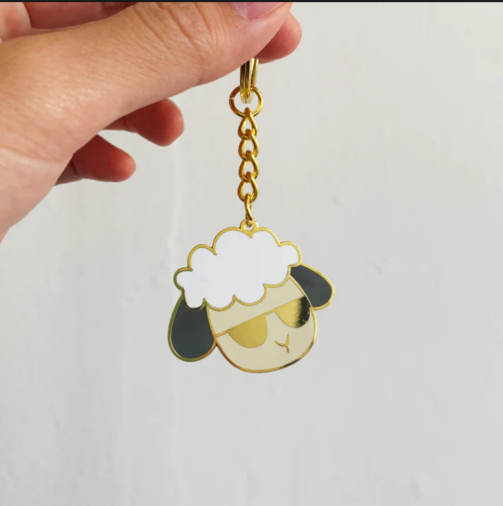 A hand holding a sheep keychain