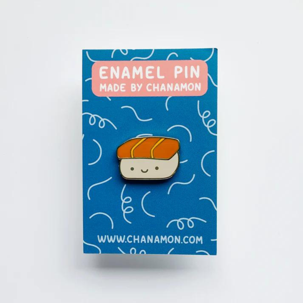 Spam Musubi Hard Enamel Pin on Backing Card with "ENAMEL PIN MADE BY CHANAMON WWW.CHANAMON.COM" text